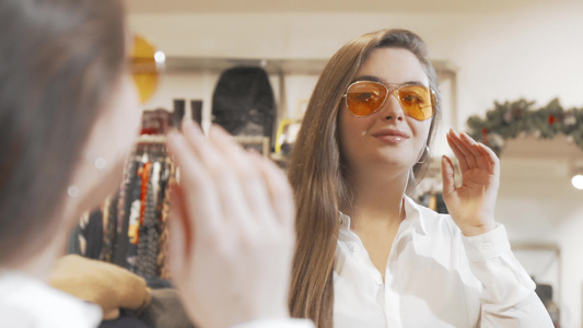 可爱的年轻美女在时装店试戴新墨镜视频