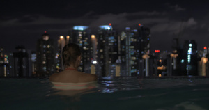 夫妻在摩天大楼屋顶的游泳池里看夜市风景48秒视频