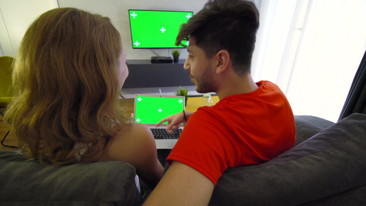 用绿色屏幕笔记本电脑和电视机在客厅的一对夫妇视频