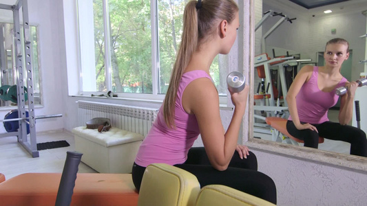 在健身俱乐部年轻女子做哑铃锻炼视频