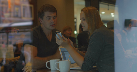 青年人使用智能电话和在咖啡馆聊天视频
