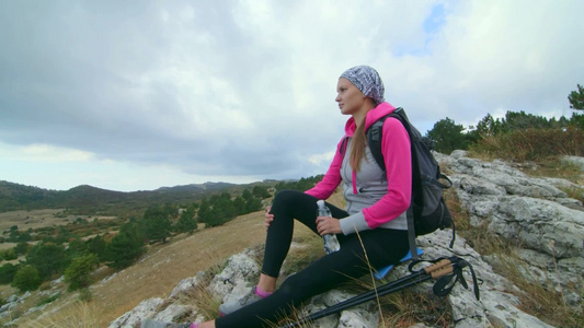 在山顶登山的年轻女性登山坐在悬崖边缘高原风景视频