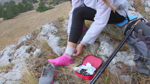 妇女在山上徒步时受伤用急救包将脚踝缠上绷带13秒视频