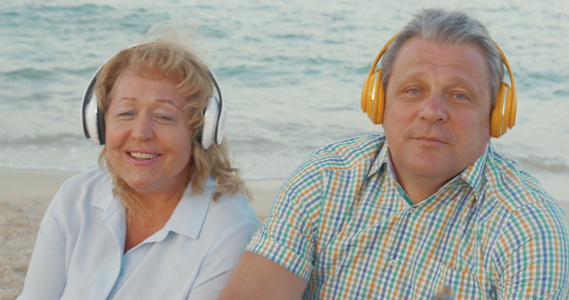在海滩上享受音乐的老年夫妇视频