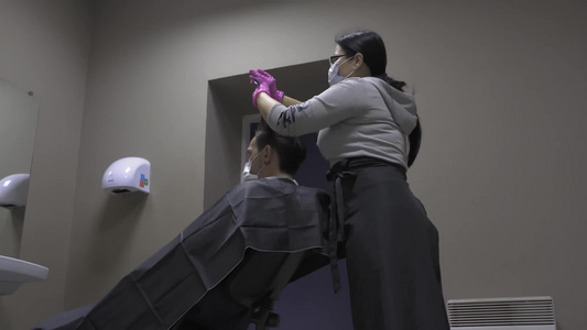 后视专业美发师准备在耳朵后面剪头发给一个年轻人做时髦视频