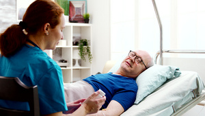 向躺在医院床男病人提供处方药的疗养院护理员15秒视频