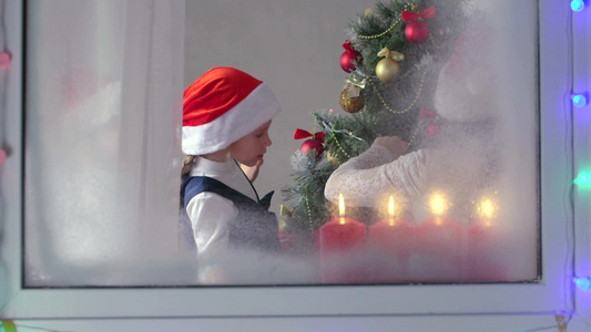 透过窗户观看圣诞树和正在装饰圣诞树的孩子视频