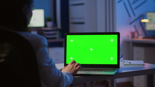 妇女晚上用绿色模型看笔记本电脑视频