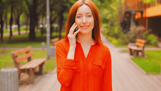 红长发女人在城里用电话聊天视频
