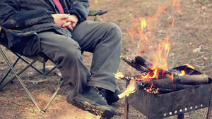 坐在营椅上的人火附近外面的娱乐活动森林里的营火9秒视频