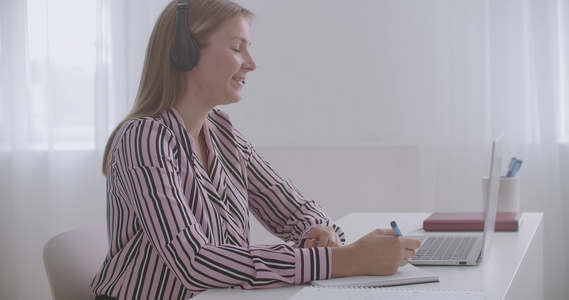 年轻女性专家通过笔记本电脑视频聊天使用耳机在网上进行视频