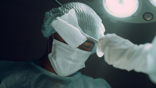 外科医生在黑暗的诊所病房进行艰苦的手术视频