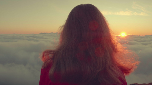 在五颜六色的粉红色日出时孤独的年轻女子站在云层之上视频