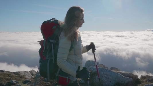 阳光明媚的日子里背着背包和登山杖的年轻微笑白种女人视频