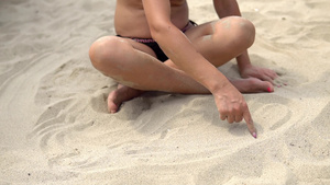 女性模特坐在沙滩沙沙上用手指写信息慢动作30秒视频
