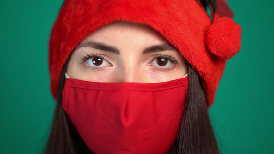 年轻女性的肖像与红色医疗面罩和圣塔帽看相机视频