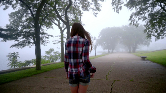 年轻妇女在公园雾中行走女孩在雾树中行走视频