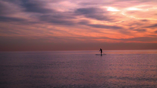 海上的日落日落时冲浪板上的人海上日落日落景观[文化景观]视频