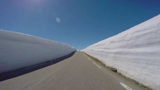 阳光下在挪威一条雪山路上驾驶一辆汽车视频