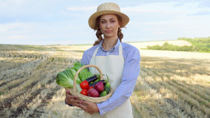 女农民草帽拿着篮子蔬菜洋葱番茄沙拉黄瓜站在农田微笑27秒视频