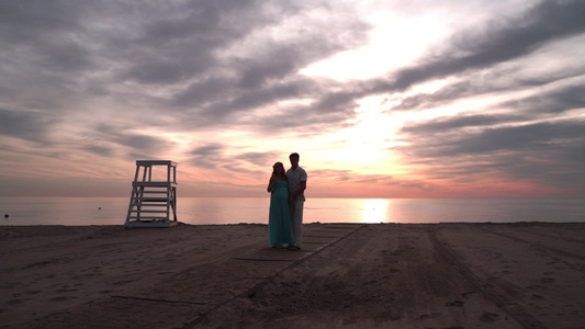 日落时谈恋爱的怀孕夫妇情概念海边的浪漫情侣视频