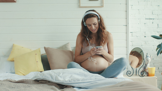 怀孕孕妈在家里给肚子里的宝宝进行音乐胎教视频