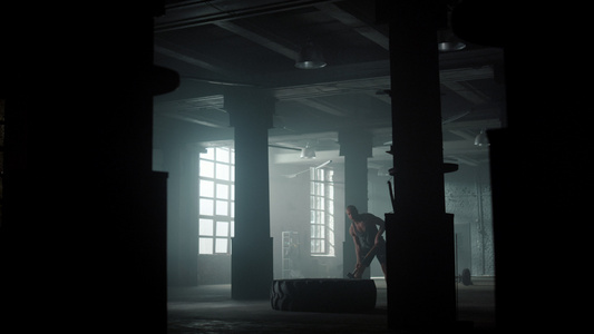 健身男性在阁楼建筑中用锤子敲打橡胶轮胎进行力量训练视频