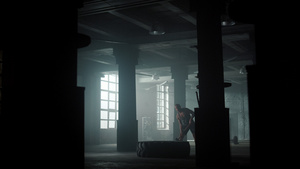 健身男性在阁楼建筑中用锤子敲打橡胶轮胎进行力量训练13秒视频