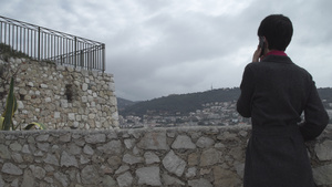 女人用智能手机站在石墙附近8秒视频