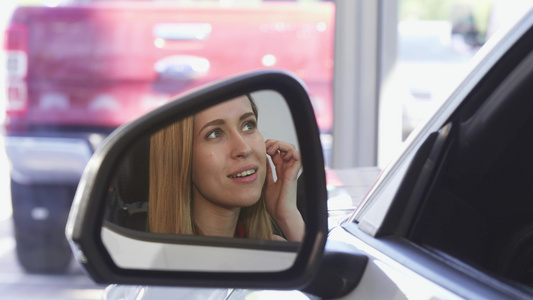 美丽的女司机微笑在侧面镜子的相机上笑视频