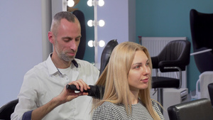 男性理发师在沙龙给女顾客卷头发8秒视频
