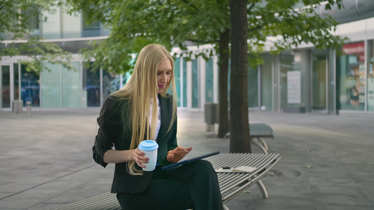 现代女执行官穿着西装坐在户外的长椅上冲浪板和喝咖啡视频