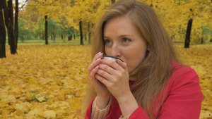 秋天树叶黄了穿着红色斗篷的年轻女子正在喝咖啡19秒视频