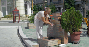 年轻女子在公共喷泉洗脸在夏天的比雷埃夫斯街上12秒视频