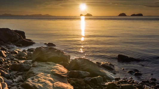 日落岩石海滩的橙色平静海视频