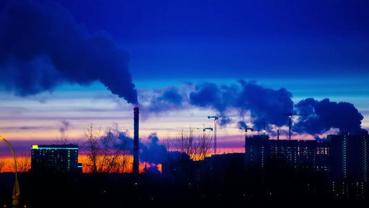 在日落的夜晚现代城市烟雾从电厂管道中冒出视频