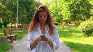 青年妇女手持手机在路上行走31秒视频