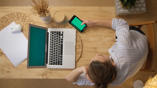 一个穿着睡衣的女孩躺在桌子上上网旁边是一台带绿屏的视频