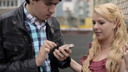 年轻男子在手机上拍摄女友在街上玩得开心的手机照片视频
