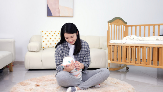 年轻妈妈坐在地毯上呵护宝宝视频