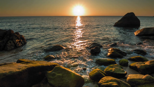 岩石海岸的橙色日落与平静的海视频