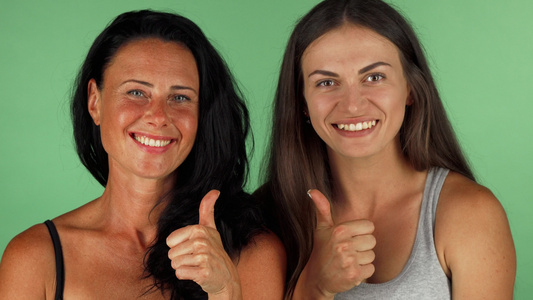 两个美丽的女人笑着露出大拇指在染色体上视频