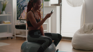 坐在健身球上的黑皮肤女人在电话中写信息11秒视频