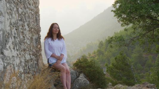 无忧无虑的女人坐在石雾上山地风景视频