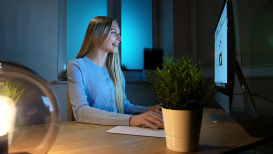微笑的女人晚上在电脑上工作穿着格子衬衫的微笑女性坐在视频