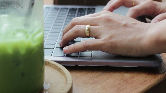 妇女用笔记本电脑打字和喝冰红绿茶视频