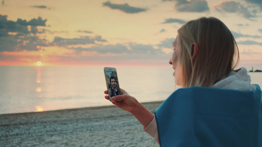 年轻女子在海滩上用智能手机打视频电话给朋友视频