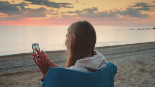 年轻女子在岸上用智能手机打视频电话视频