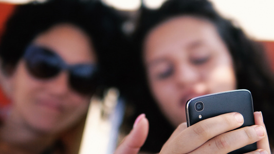 青少年在沙滩床上的智能手机上微笑预览社交媒体帖子有视频