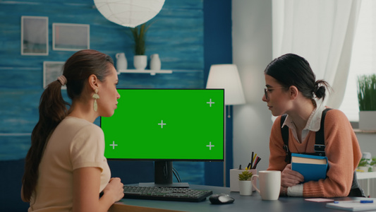两名妇女用绿色屏幕模拟电脑观看计算机视频